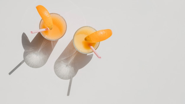 Free Photo glasses of natural juice of oranges with shadows top view