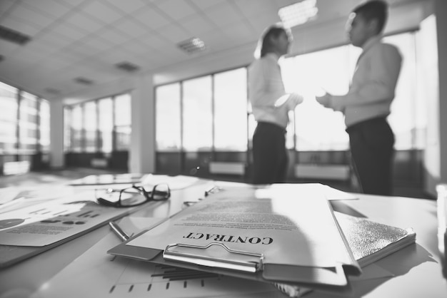 Glasses on a office desk with employees talking