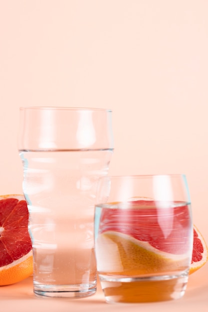 Glasses of water with half red oranges