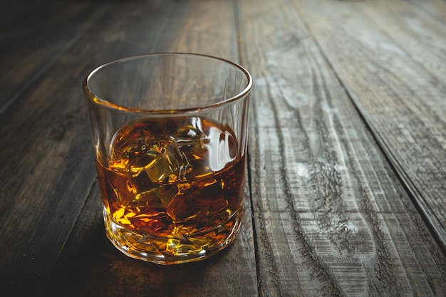 Free photo glasses of whiskey with ice cubes on wood.