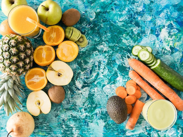 Glasses with detox juice next to fruits and vegetables on wooden background