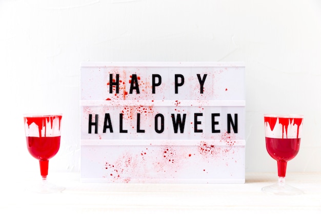 Free Photo glasses with fake blood near happy halloween writing