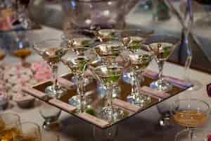 Free photo glasses with martini and green olives stand on mirror tray