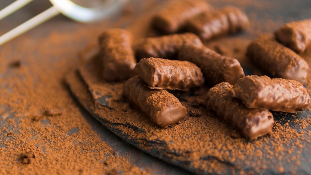 Glazed chocolate biscuits covered with cocoa powder on black plate