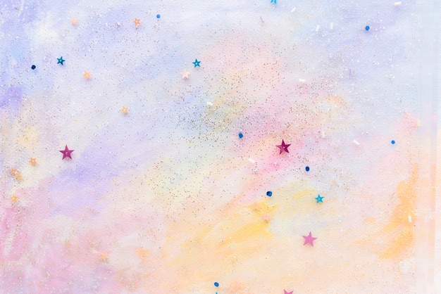 Free photo glittery star confetti on colorful abstract pastel watercolor background