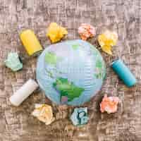 Free photo globe surrounded by garbage on wooden surface