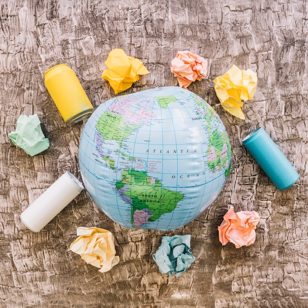 Free Photo globe surrounded by garbage on wooden surface