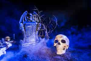 Free photo gloomy skull placed near headstone in fog on ground