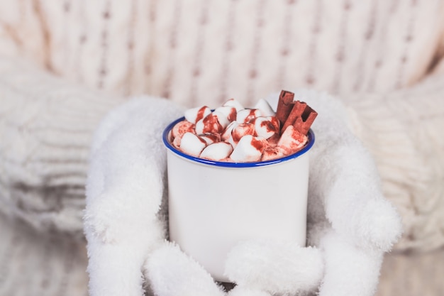 Gloved hands holding a cup with marshmallows