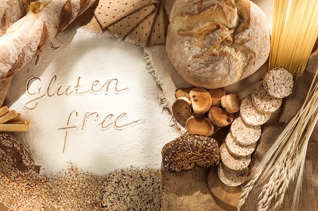 Gluten free food. Various pasta, bread and snacks on wooden background from top view