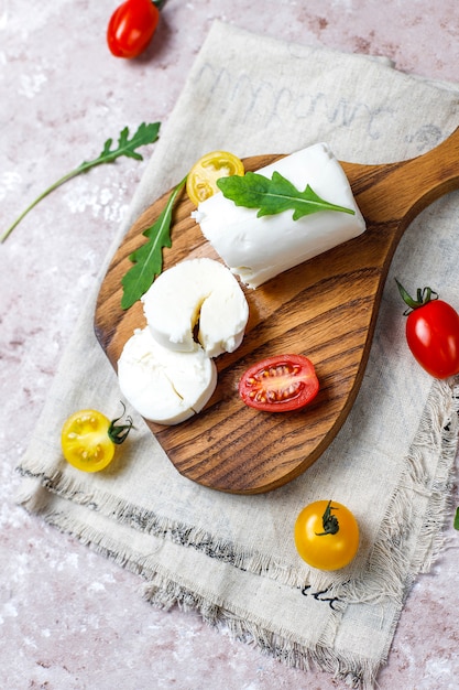 Free photo goat cheese slices on wooden board with ruccola,cherry tomatoes. ready to eat.