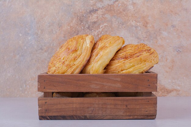 Gogal buns in a wooden tray on white surface