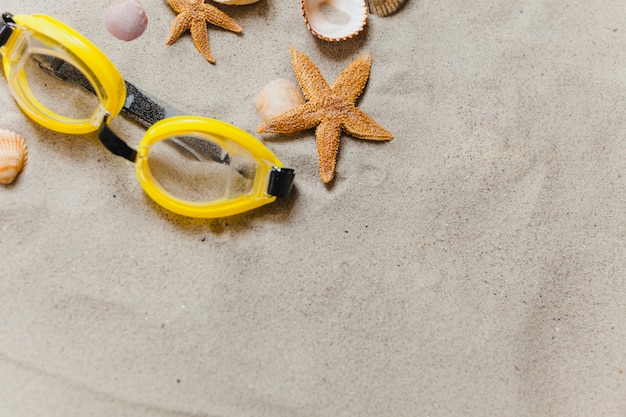 Free photo goggles on the sand with starfish