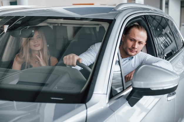 Going back. Positive manager showing features of the new car to female customer