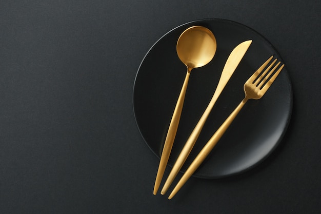 Free photo gold cutlery set on black background