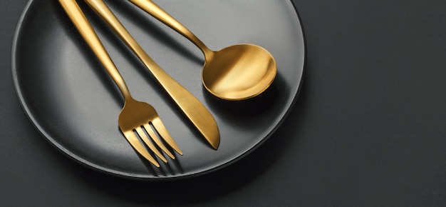 Gold cutlery set on black background