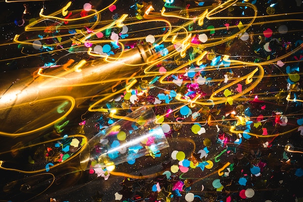 Golden bottle and champagne glass on confetti background