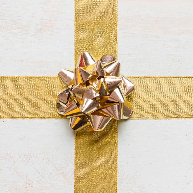 Free photo golden bow and ribbons on white tabletop