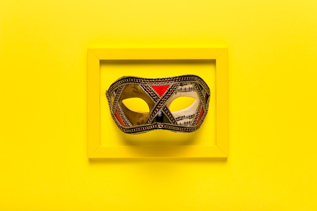 Free photo golden carnival mask in yellow frame