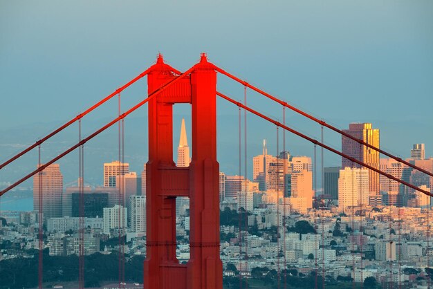 Golden Gate Bridge closeup with San Francisco downtown at sunset.