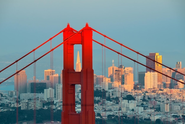 Golden Gate Bridge closeup with San Francisco downtown at sunset.