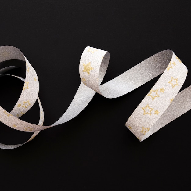 Golden star shape on silver ribbon over the black background