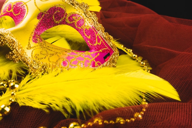 Golden venetian mask with feathers on a red fabric