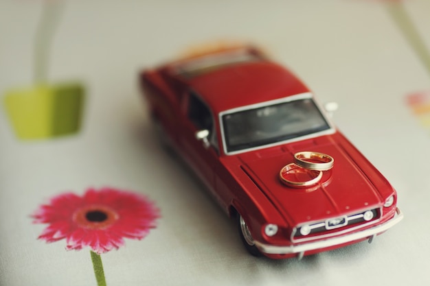 Free Photo golden wedding rings lie on a toy red mustang 