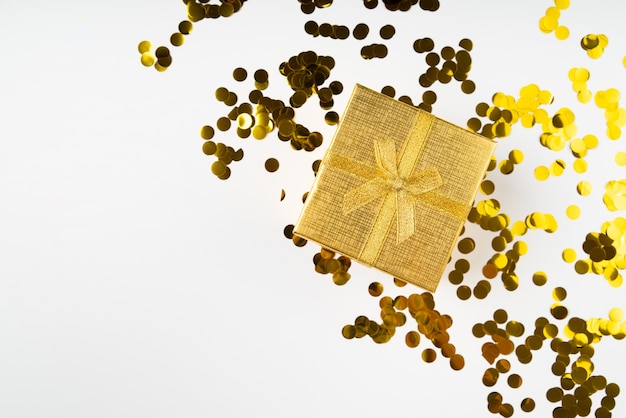 Free photo golden wrapped gift surrounded by confetti