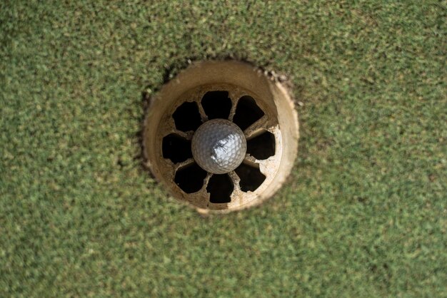 Golf field with white ball inside the hole