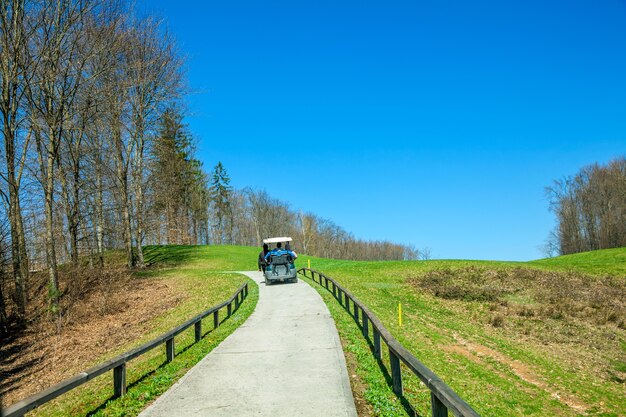 Free photo golf truck riding through the path in the golf course in otocec, slovenia