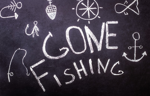 Gone fishing chalk inscription on chalkboard with marine drawings