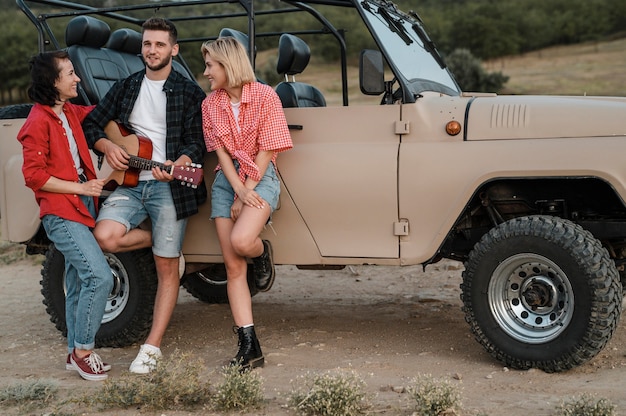 Free photo good friends playing guitar while traveling by car