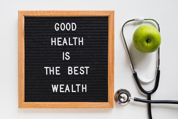 Free Photo good health message board with green apple and stethoscope on white background