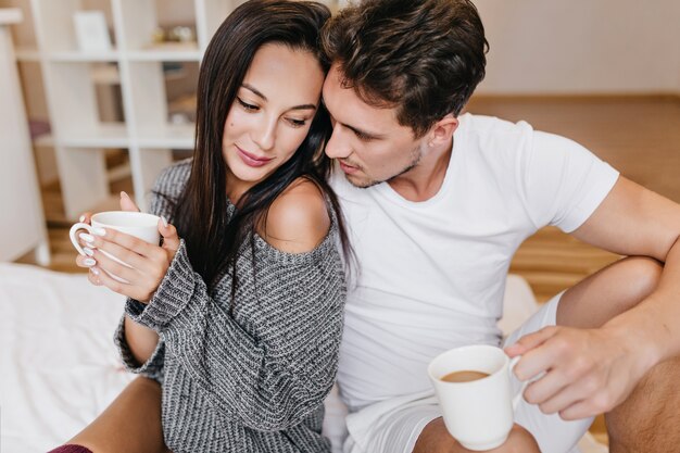 Good-looking man drinking cappuccino and talking with romantic womanfriend