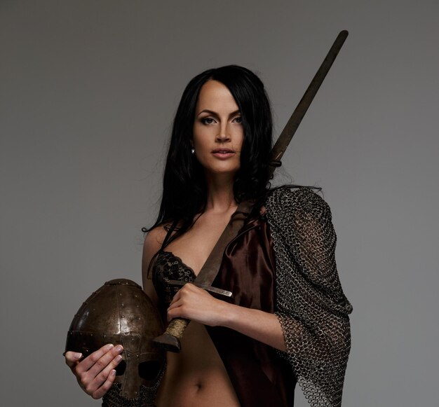 Goregeous female warrior poses holding sword and helmet