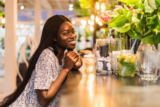 Gorgeous african woman drinking lemonade sitting in cafe.