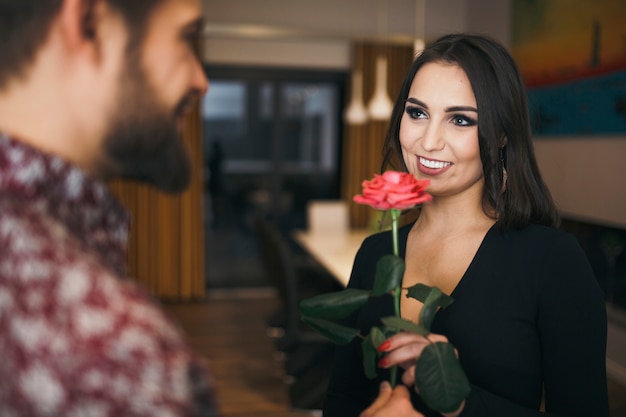 Gorgeous brunette getting pink rose from man