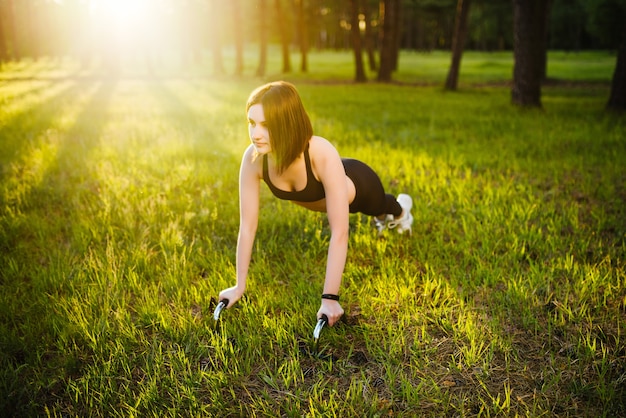 Gorgeous brunette warming up and doing some push ups on nature