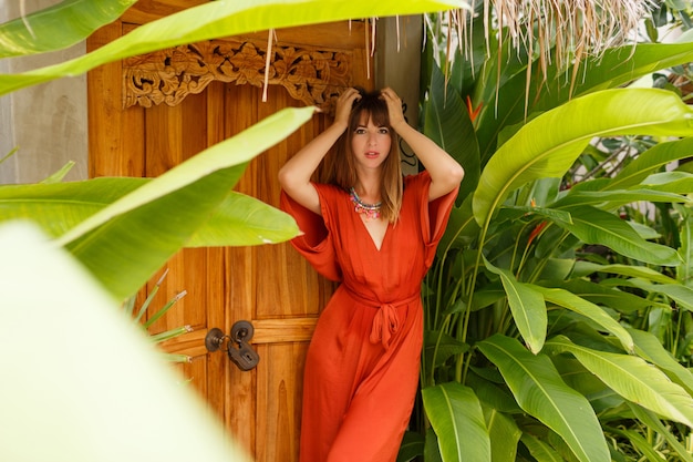 Free photo gorgeous  brunette woman in stylish summer outfit  enjoing vacation in luxury resort. exotic  garden with tropical plants.