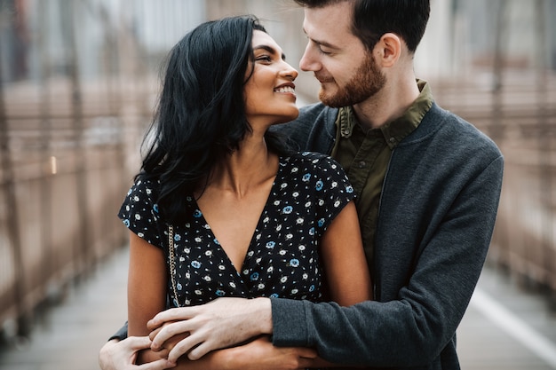 Gorgeous couple of American man with beard and tender Eastern woman hug each other