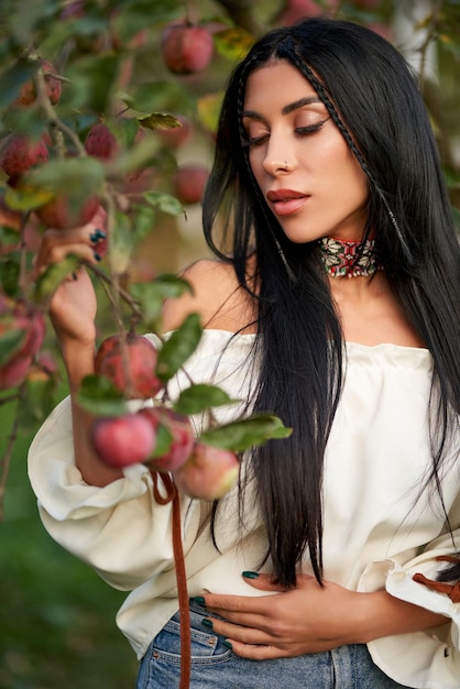 Free photo gorgeous female gardener picking apples in apple orchard