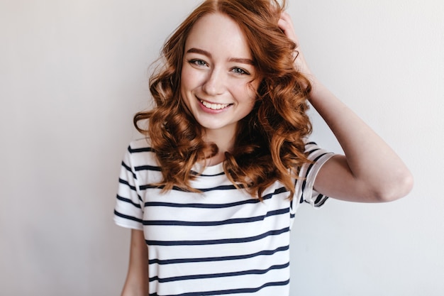 Gorgeous female model with happy face expression standing. Indoor photo of active positive woman with ginger hair.