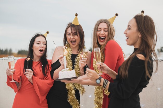 Gorgeous girls holding the birthday cake on a rooftop party