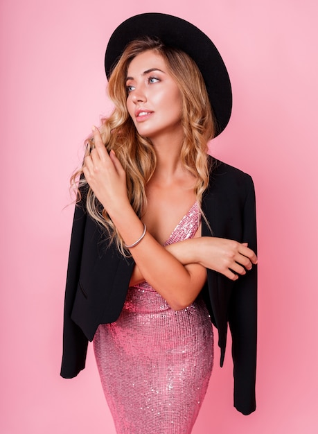 Free Photo gorgeous graceful woman with healthy blond wavy hairs standing over pink wall.