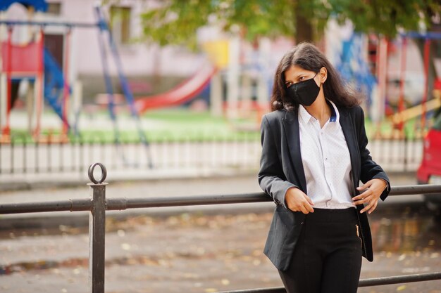 Gorgeous indian woman wear formal and black face mask posing at street during covid pandemia