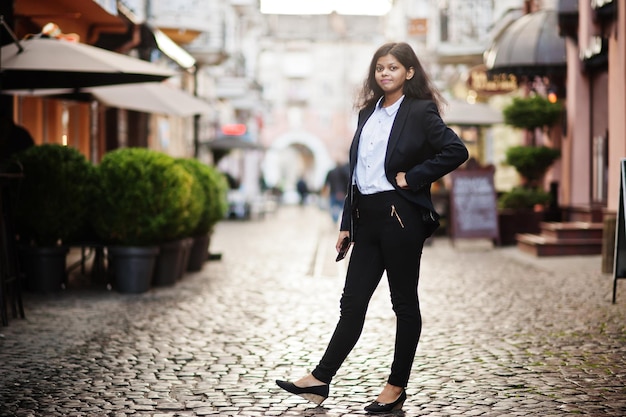 Gorgeous indian woman wear formal posing at street with mobile phone at hands