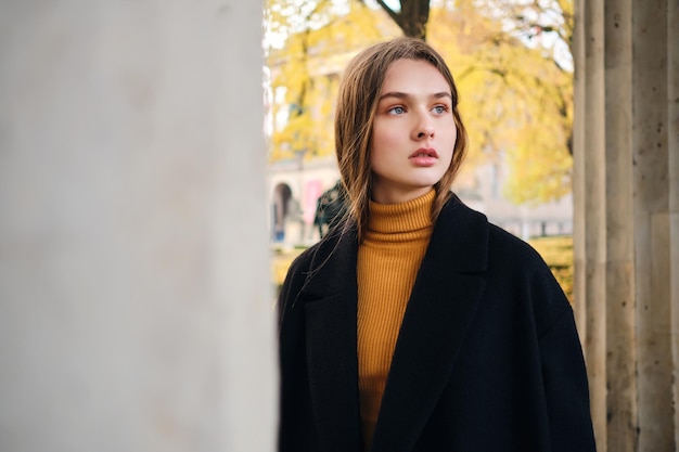 Free photo gorgeous stylish girl dreamily looking away walking alone through autumn city street