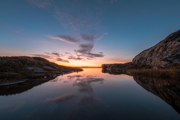 Free photo gorgeous view of a calm lake surrounded by rocks, with the sky reflected on the water during sunset