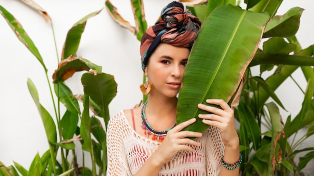 Free photo gorgeous woman with turban on head, colorful earrings and boho necklace posing